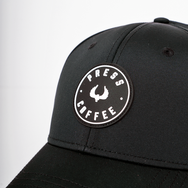 A close up shot of a Press Coffee circular logo hat.