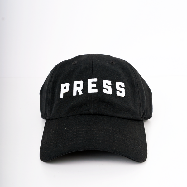 A forward facing view of a PRESS dad hat