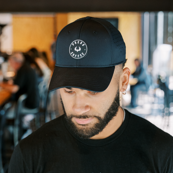 A man with a beard wearing a Press Coffee logo hat.