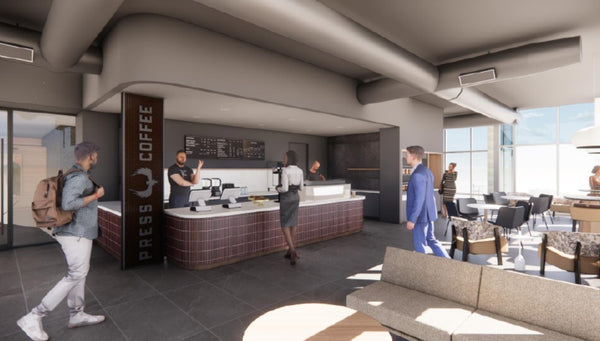 A modern interior cafe space with a counter labeled PRESS COFFEE, several people walking and standing, seating areas with tables and chairs, large windows, and exposed ceiling ducts.