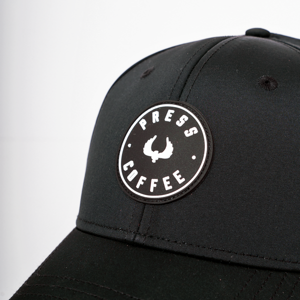 A close up shot of a Press Coffee circular logo hat. 