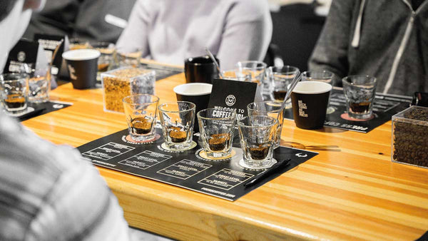 Coffee 101 table spread including ground coffee, cups, placemats, spoons, and more. 