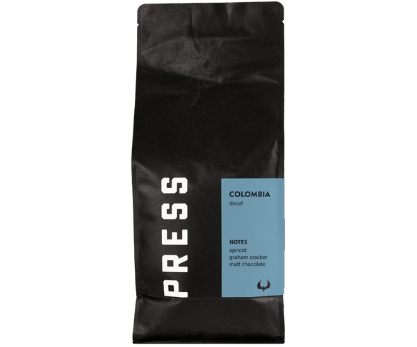 Black coffee bag with 'PRESS' branding and Colombia decaf information on a white background