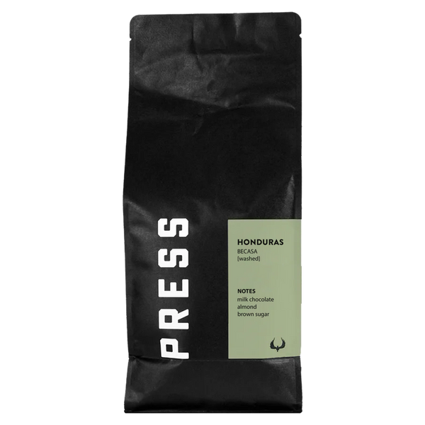 Black coffee bag with green label featuring the brand 'PRESS' and coffee details on a white background
