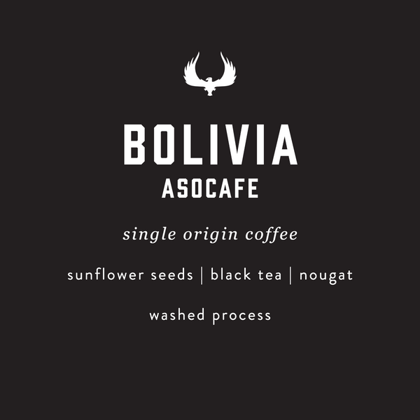 A dark charcoal background with white text reading 'BOLIVIA ASOCAFE' and smaller text below listing ingredients and processing: 'single origin coffee', 'sunflower seeds | black tea | nougat', and 'washed process'. A white winged logo appears above the main text.
